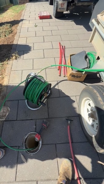 Hose reels and plumbing gear set up on a tiled driveway