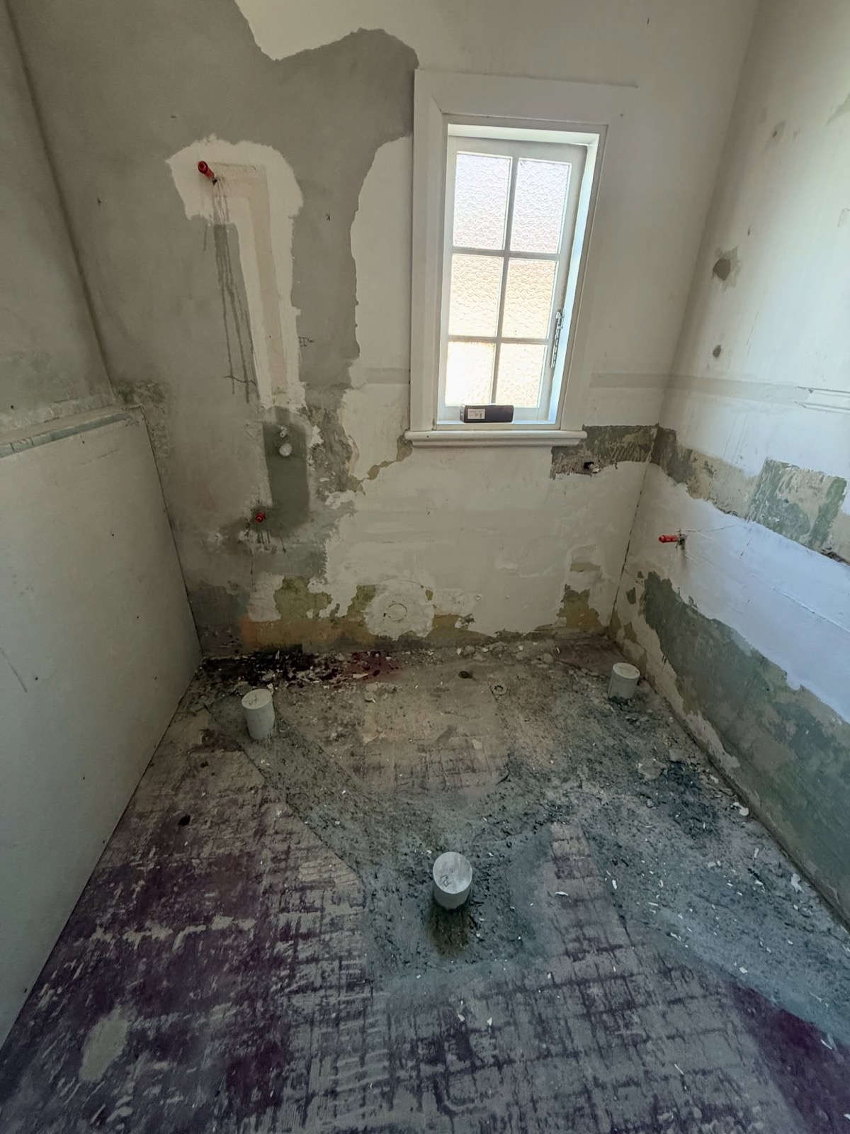 A room mid-renovation with exposed wall framing and old pipework