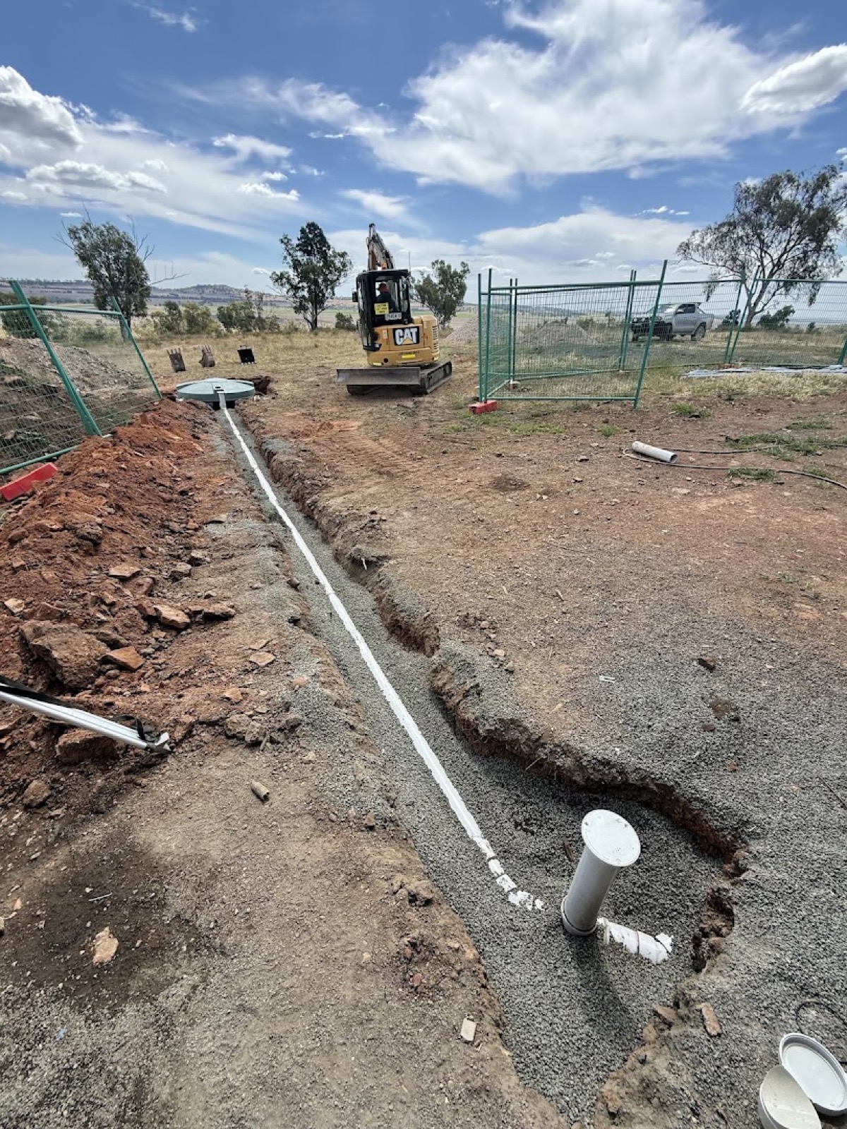 A trench dig with new pipework and an excavator on a fenced Tamworth-region site